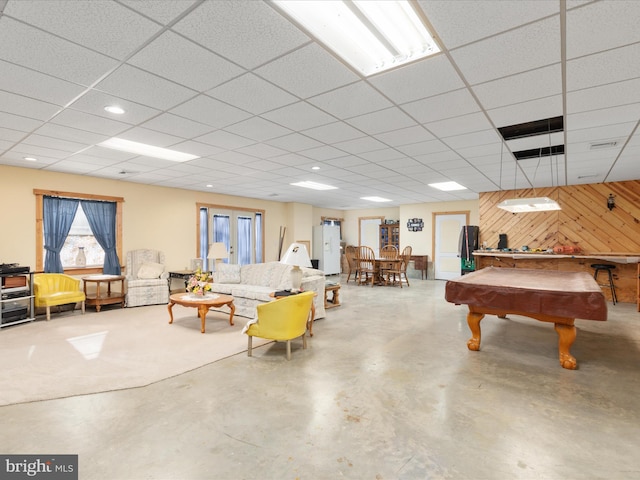 playroom featuring wooden walls, a drop ceiling, concrete floors, and pool table