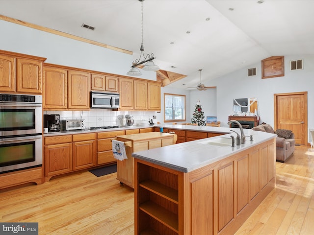 kitchen featuring a kitchen island with sink, sink, light hardwood / wood-style flooring, vaulted ceiling, and stainless steel appliances