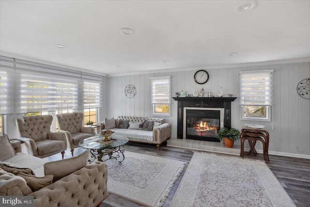 living room featuring wooden walls, hardwood / wood-style flooring, and ornamental molding