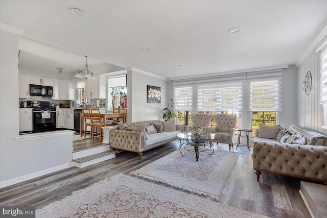 living room featuring a chandelier, wood-type flooring, and ornamental molding