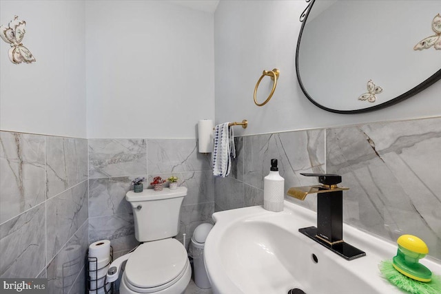 bathroom with sink, tile walls, and toilet