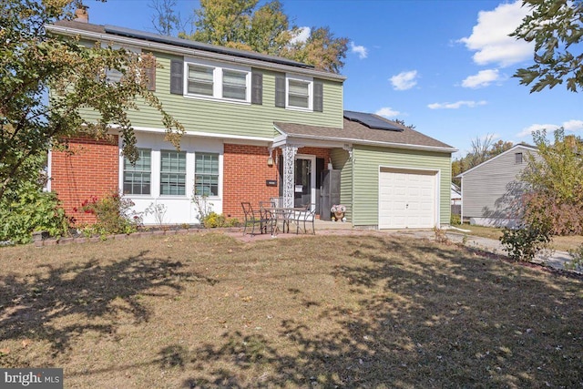 view of front of home featuring solar panels, a garage, a patio, and a front yard