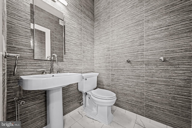 bathroom with toilet and tile walls