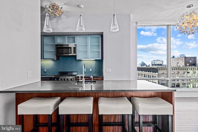 kitchen with pendant lighting, dark wood-type flooring, sink, decorative backsplash, and a breakfast bar area