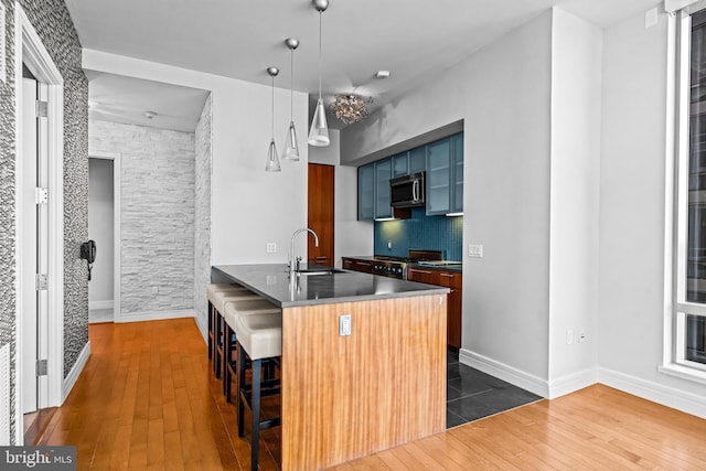 kitchen featuring kitchen peninsula, appliances with stainless steel finishes, sink, dark hardwood / wood-style floors, and a breakfast bar area