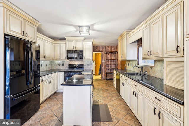 kitchen with sink, tasteful backsplash, cream cabinetry, a kitchen island, and black appliances