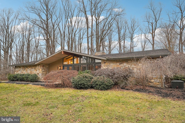 view of property exterior featuring a lawn, central air condition unit, and a sunroom