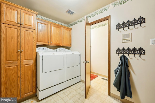 clothes washing area with washer and clothes dryer and cabinets