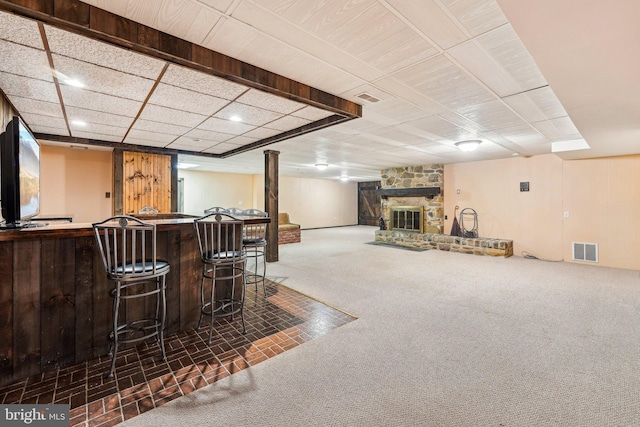 bar featuring dark colored carpet and a stone fireplace