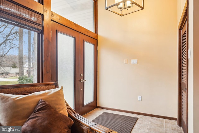 tiled entryway with french doors and a notable chandelier