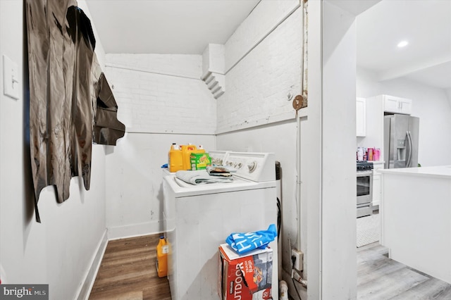 clothes washing area featuring washer / clothes dryer and light wood-type flooring