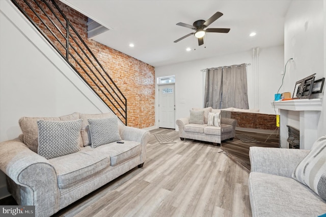 living room with light wood-type flooring, ceiling fan, and brick wall