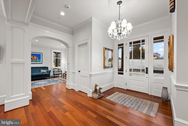 foyer entrance featuring an inviting chandelier, wood-type flooring, and ornamental molding