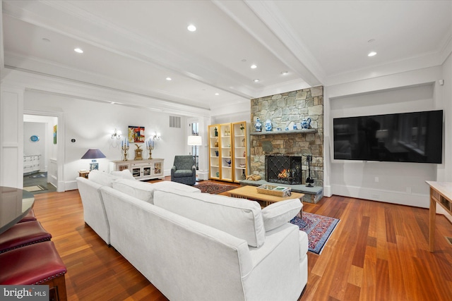 living room featuring beamed ceiling, crown molding, wood-type flooring, and a fireplace