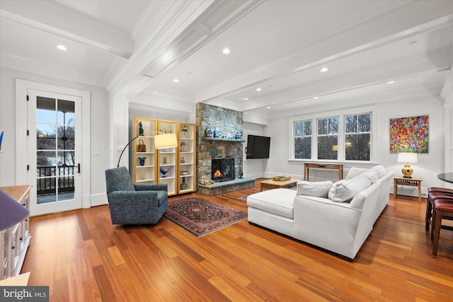 living room with a stone fireplace, ornamental molding, light hardwood / wood-style floors, and beamed ceiling