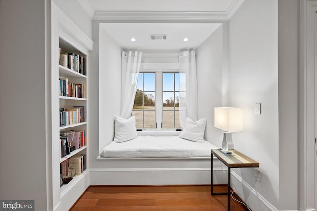 living area with crown molding and hardwood / wood-style flooring