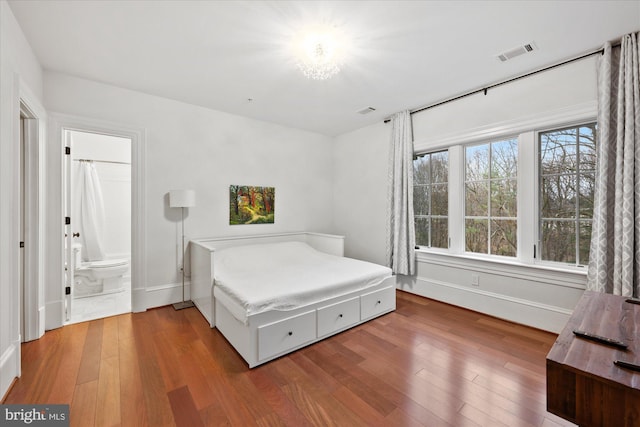 bedroom with wood-type flooring and connected bathroom