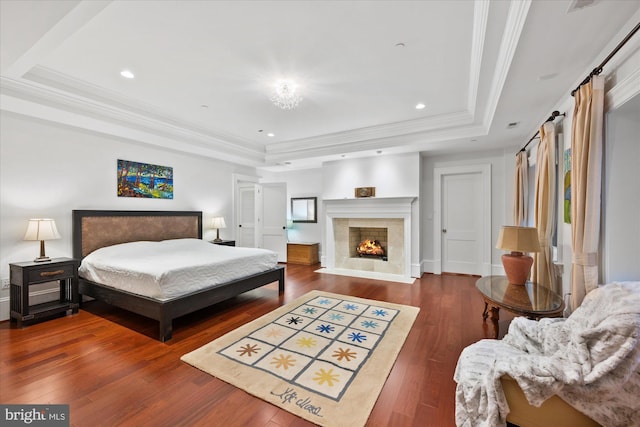 bedroom featuring a fireplace, ornamental molding, dark hardwood / wood-style floors, and a raised ceiling