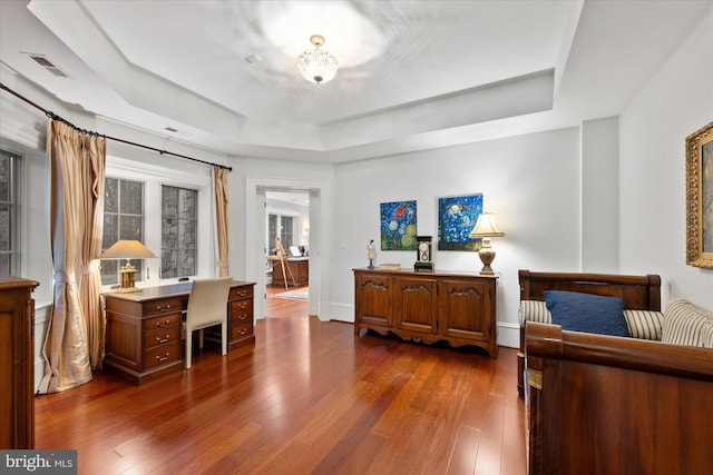 bedroom featuring dark hardwood / wood-style floors and a tray ceiling