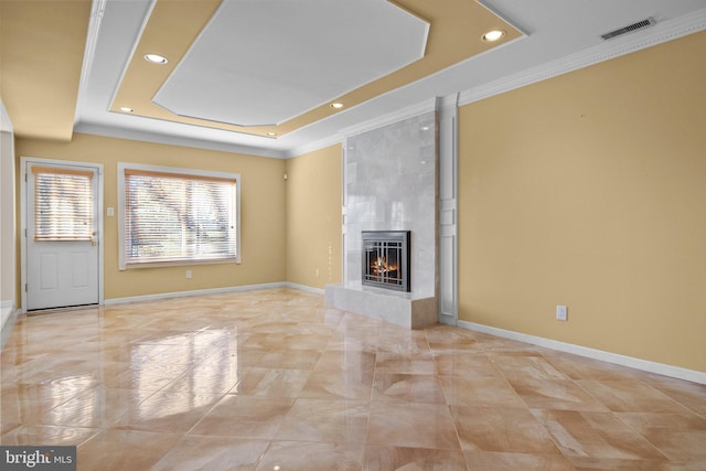 unfurnished living room with a tray ceiling, a tile fireplace, and crown molding