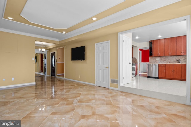 empty room with a raised ceiling, sink, an inviting chandelier, and ornamental molding