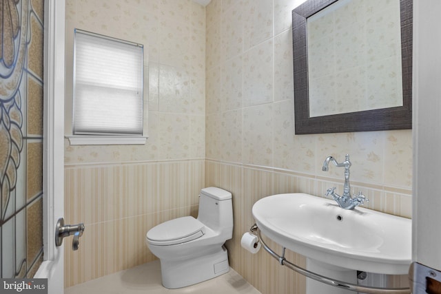 bathroom with tile patterned floors, toilet, tile walls, and sink