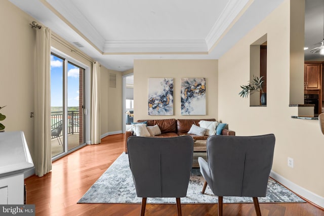 living room featuring light hardwood / wood-style floors, a tray ceiling, and crown molding