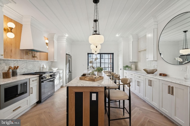 kitchen featuring light stone counters, light parquet floors, white cabinets, and high end appliances