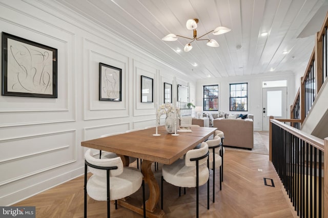 dining area with light parquet floors, a notable chandelier, and crown molding