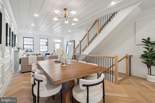 dining room with a chandelier, ornamental molding, and light parquet floors