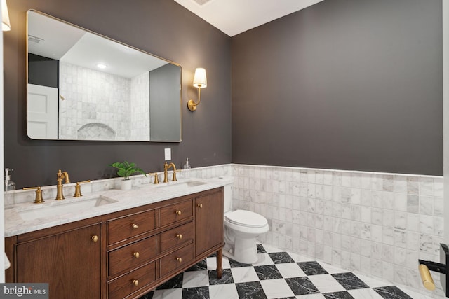 bathroom with vanity, toilet, and tile walls