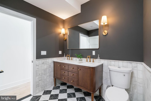 bathroom with vanity, toilet, and tile walls