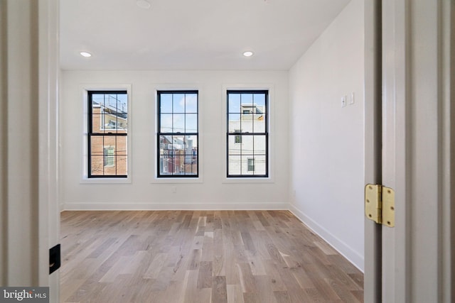 empty room with a wealth of natural light and light hardwood / wood-style flooring