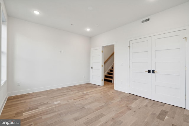 unfurnished bedroom with light hardwood / wood-style flooring and a closet