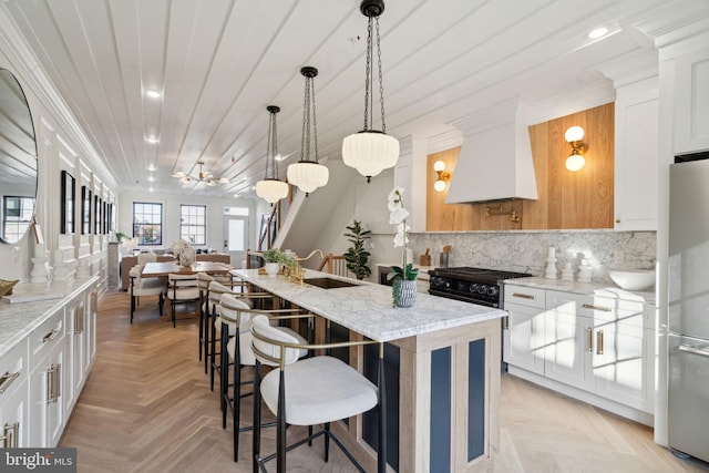 kitchen with stainless steel fridge, custom range hood, a kitchen island, ceiling fan, and white cabinetry