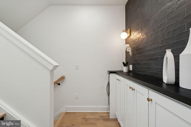 bathroom with tasteful backsplash, hardwood / wood-style floors, and lofted ceiling