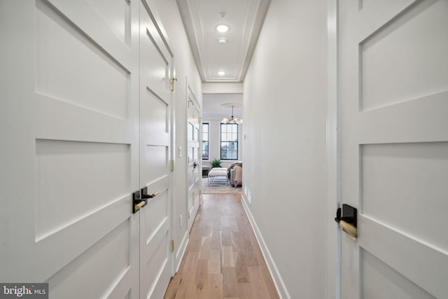 corridor with an inviting chandelier and light hardwood / wood-style flooring