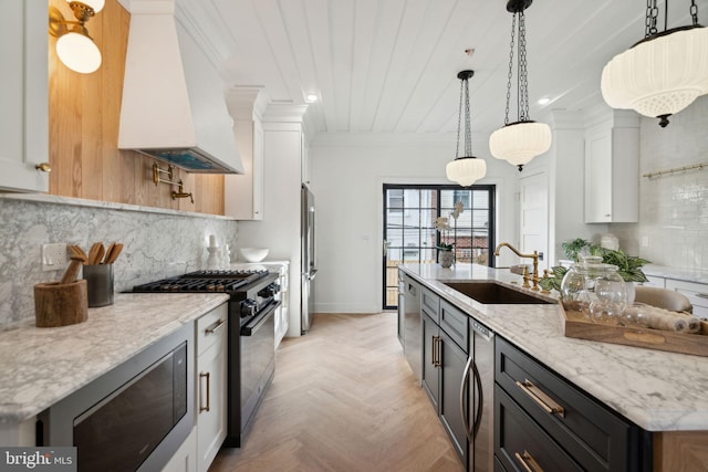 kitchen with premium range hood, stainless steel appliances, a center island with sink, white cabinetry, and hanging light fixtures