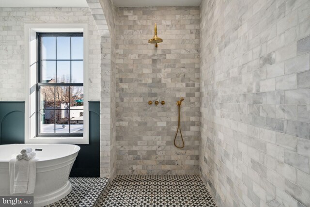 bathroom featuring independent shower and bath, tile walls, and a wealth of natural light