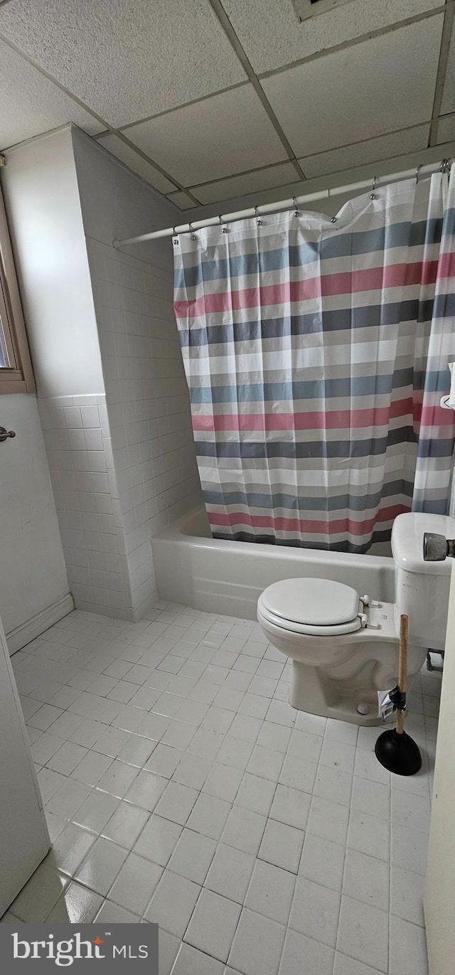 bathroom with toilet, tile patterned floors, a paneled ceiling, and shower / tub combo with curtain