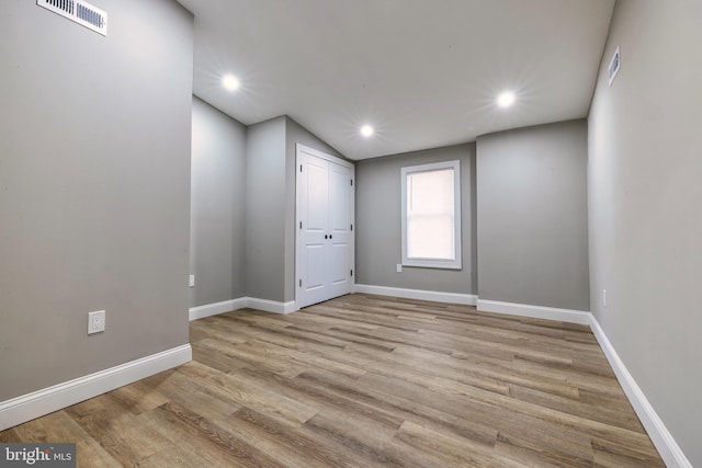 empty room featuring lofted ceiling and light wood-type flooring