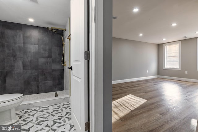 bathroom featuring hardwood / wood-style floors, toilet, and a tile shower