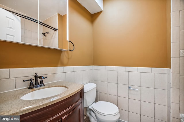 bathroom featuring vanity, tile walls, and toilet