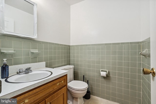 bathroom with vanity, toilet, and tile walls