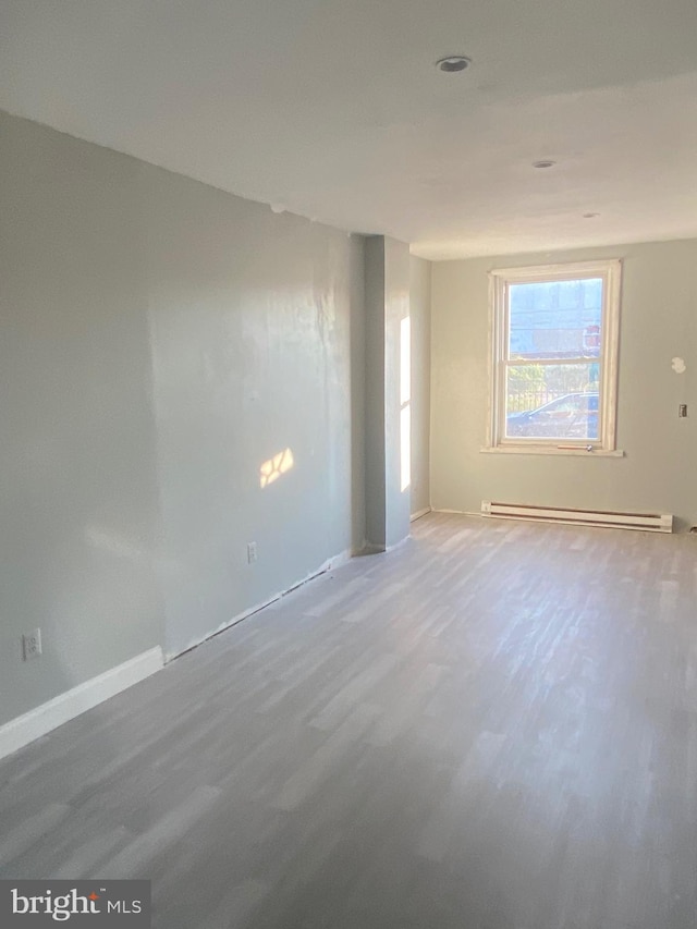 empty room with hardwood / wood-style floors and a baseboard heating unit