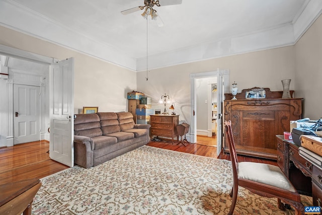 living room featuring ceiling fan, ornamental molding, and light wood-type flooring