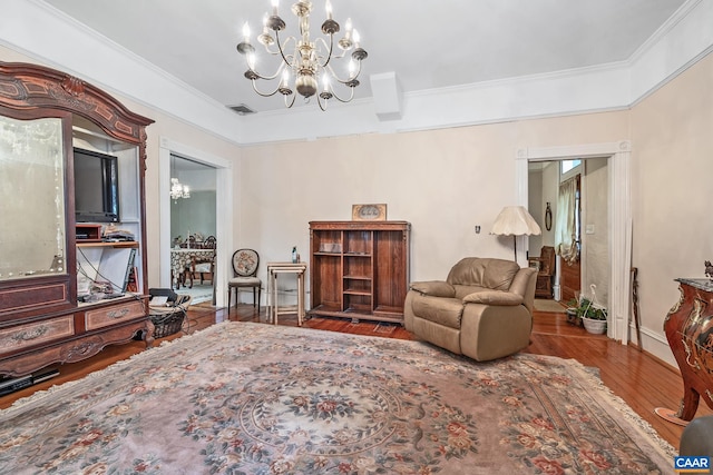 living area featuring wood-type flooring, ornamental molding, and an inviting chandelier