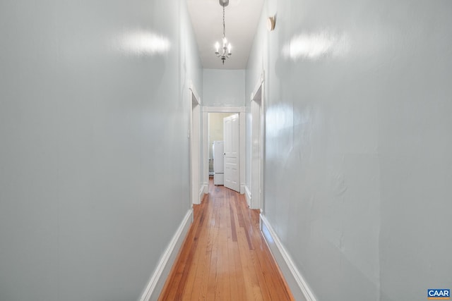 hall with hardwood / wood-style flooring, washer / dryer, and a chandelier