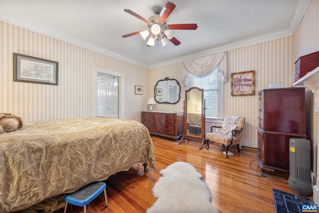 bedroom with ceiling fan, hardwood / wood-style floors, a textured ceiling, a closet, and ornamental molding