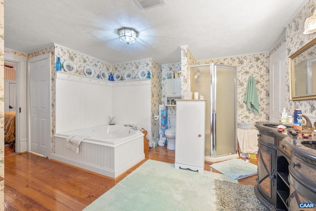 full bathroom with shower with separate bathtub, hardwood / wood-style floors, a textured ceiling, and toilet